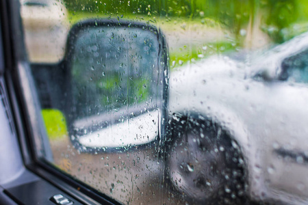 雨点落在车上。侧面镜的内部视图