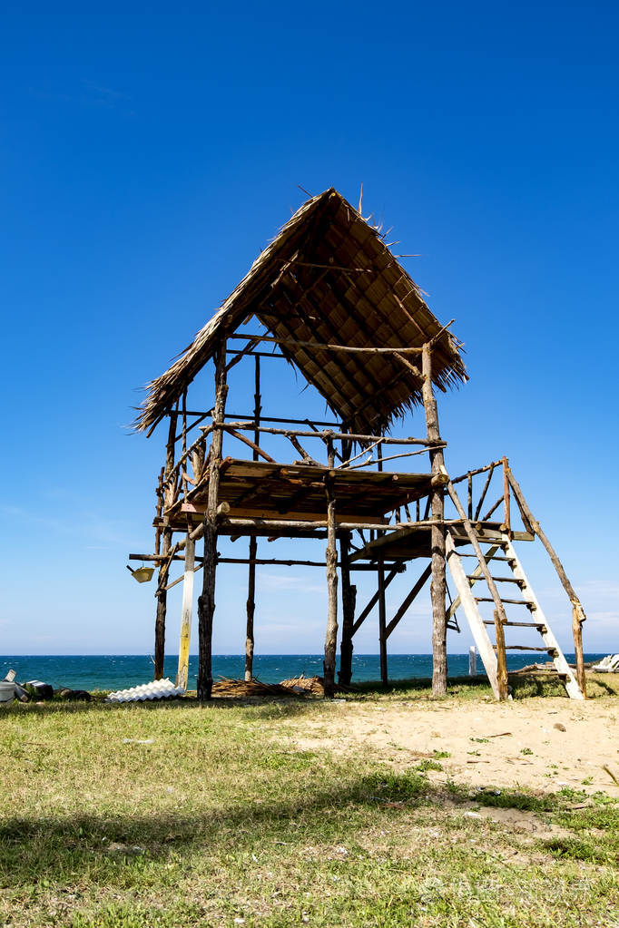 热带沙滩和蓝天背景下阳光明媚的一天木屋