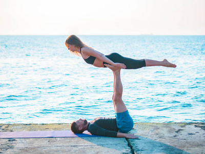 男人躺在水泥板上, 平衡女人的脚.美丽的一对练习瑜伽一起照片