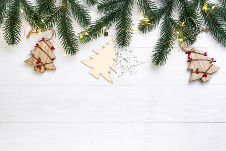 圣诞作文。圣诞冷杉树枝和木制圣诞树, 白色背景上有灯光。平面放置, 顶部视图复制空间