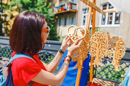 一个在纪念品交易会上的女性游客选择手工装饰木雕礼品