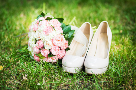 女性时尚婚礼鞋, 优雅的新娘花束在绿色的草地背景柔和色调。婚礼详情