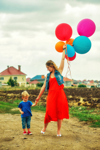 快乐的家庭在散步中玩得开心。年轻的母亲和儿子在夏天玩一个国家的气球散步