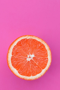 在明亮的背景紫色的一个柚子切片的最高视图。饱和柑橘纹理图像