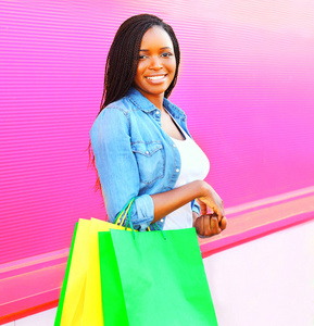 非洲妇女与购物袋在城市在多彩的粉红色背景