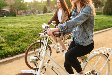两名年轻女性朋友在户外骑自行车在公园的图片