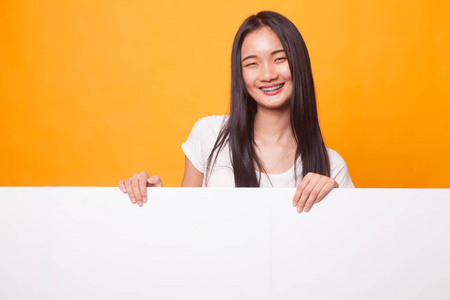 年轻的亚洲妇女与空白标志在明亮的黄色背景