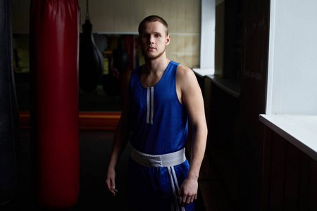 运动拳击手在蓝色运动服站立在健身房