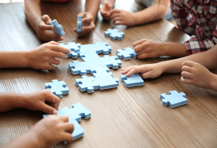 小朋友们在桌上玩拼图, 专心于手。团结理念