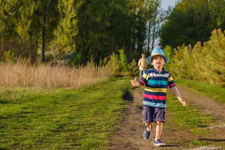 快乐的白种孩子男孩奔跑在草甸草在夏天在自然公园