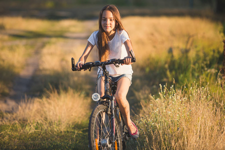 夕阳下乡村小路上美丽少女骑自行车的色调肖像
