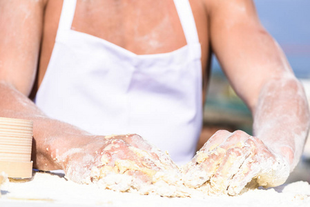 肌肉面包师或厨师手揉捏生粘面团。厨师的手用黏糊糊的面团和面粉工作。面包店的概念。面团和面粉散落各地, 关闭