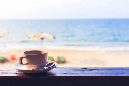 海滩附近的木材上的热咖啡杯