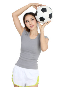 年轻的亚洲妇女在体育穿戴拿着橄榄球在她的手