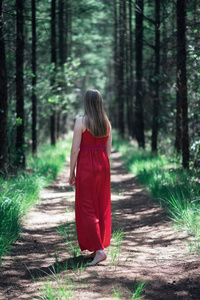 森林小路上穿着红色礼服的金发女郎