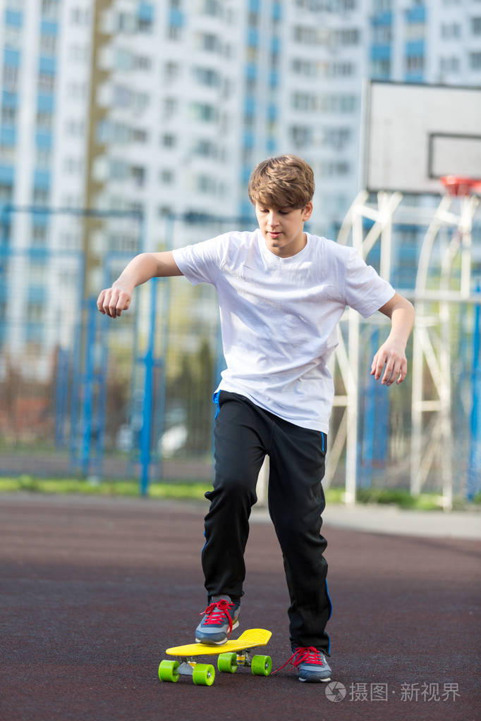 可爱的年轻运动男孩滑冰的黄色滑板, 并有一个很好的时间在他的空闲