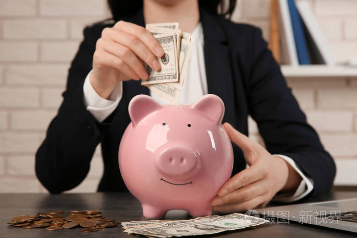 女人把钱放在桌上存钱罐里