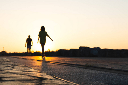 年轻夫妇赛跑者的剪影在公园在黄昏日落奔跑。人们走路和运动。健身与健康活动生活方式