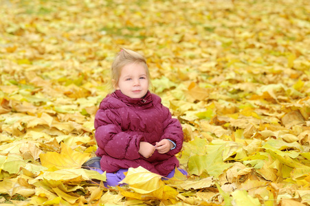 蹒跚学步女孩玩在秋天的树叶