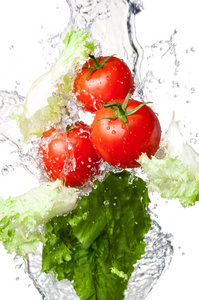 三个新鲜红番茄和生菜上孤立的飞溅水中
