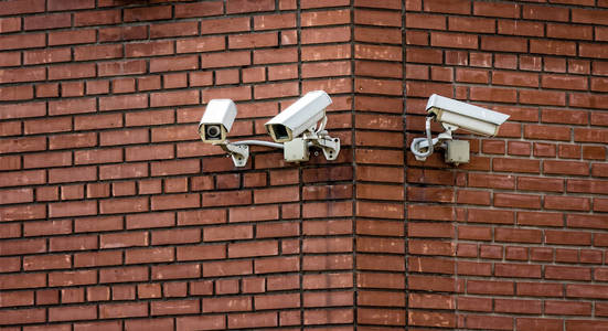 三台监控摄像头安装在建筑的砖墙上照片