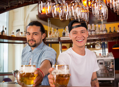 两个年轻快乐的酒保为顾客提供啤酒