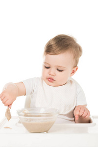 小男孩用勺子吃粥, 坐在高脚的白色背景上