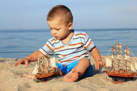 一个小男孩与一艘船在海滩上