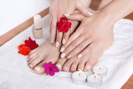 妇女的脚和手与法国修剪指甲和鲜花和蜡烛在白色的毛巾。特写, 选择性聚焦
