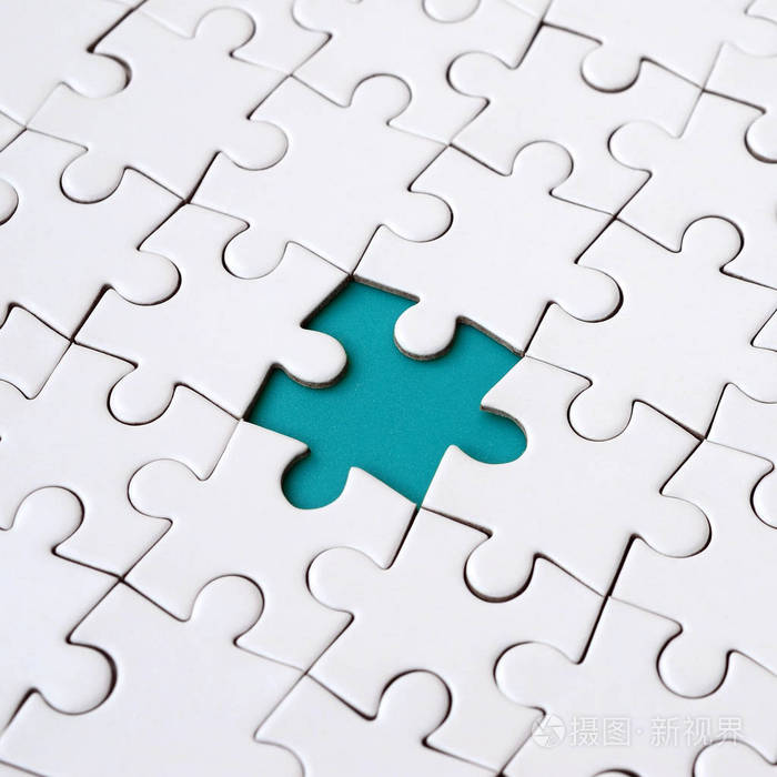 在组装状态下的白色拼图拼图的特写纹理缺少元素形成一个蓝色的文本垫