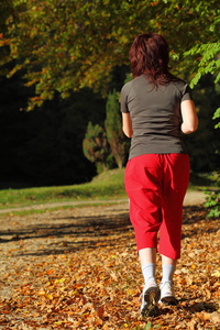 交叉郊游径在秋天的森林中散步的女人