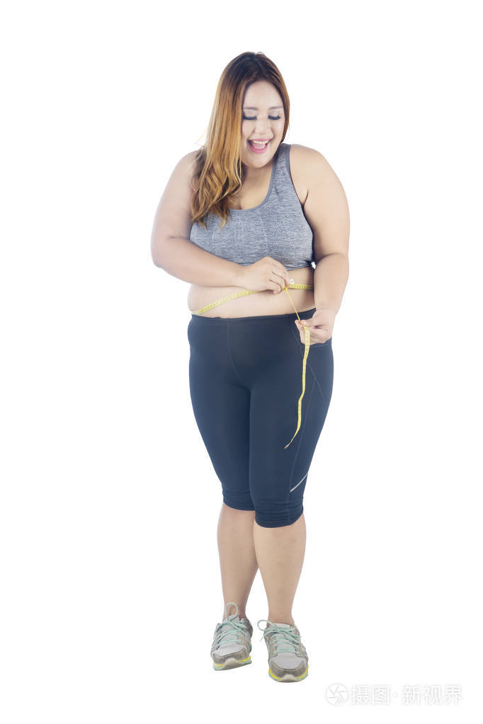 全长的肥胖妇女在测量她的腰围与测量的磁带, 被隔绝在白色背景时看