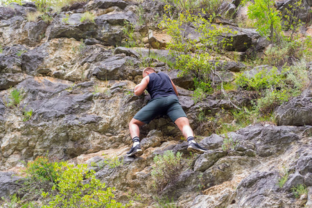 男童登山运动员穿着运动服爬上岩石登上阿尔泰山的顶端没有设备和保险