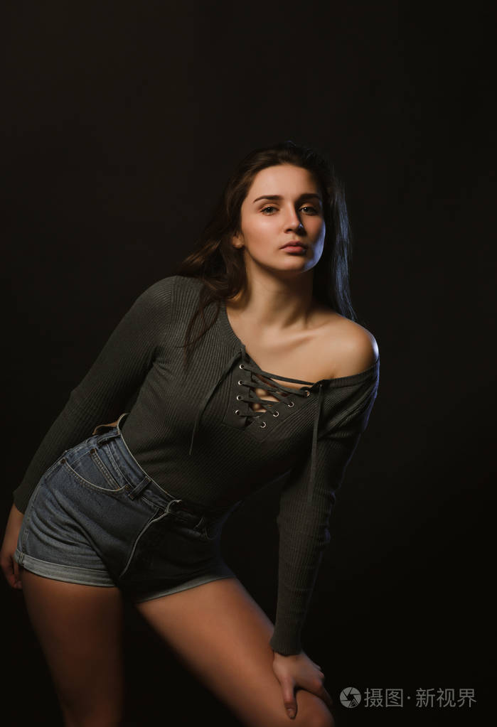时尚模特测试拍摄的诱人的女人身着灰色内衣和牛仔裤短裤在黑暗的工作