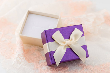 小紫色首饰礼品盒与弓在花边背景。戒指用纸盒