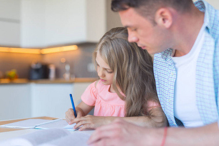 年轻的爸爸和一个小女儿在家做家庭作业
