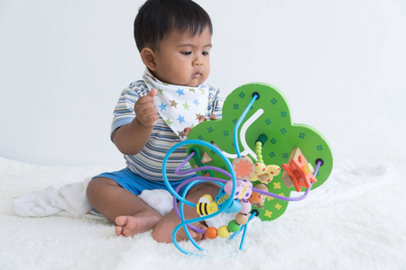 可爱的亚洲婴儿坐和玩木制玩具