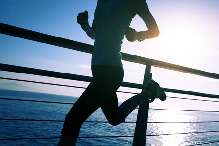 运动的健身女性赛跑者在海滨木板路上奔跑在日出