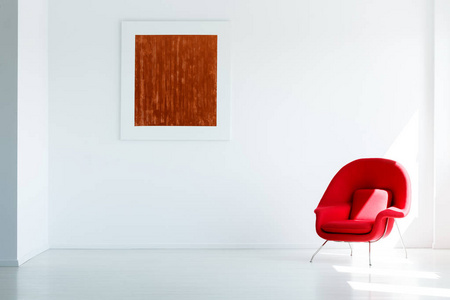 红色绘画在白色墙壁在宽敞空的阁楼内部与现代扶手椅。真正的照片与一个地方为您的沙发