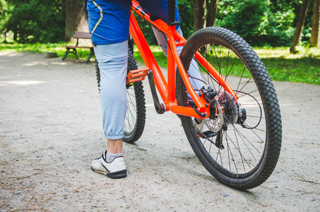 骑自行车的腿和在泥土路上的自行车的一部分照片