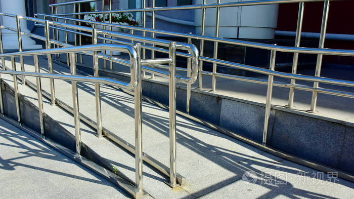 斜坡与不锈钢围栏和镀铬金属结构残疾人轮椅用户, 手推车与货物和神