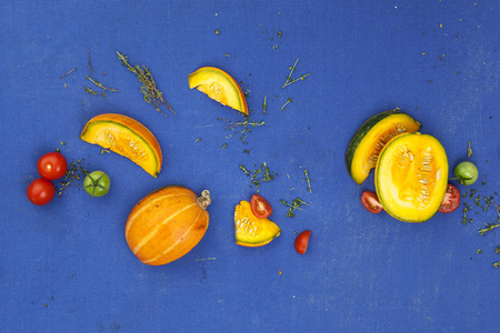 食品概念背景。蓝桌上的南瓜西红柿和百里香。顶部视图