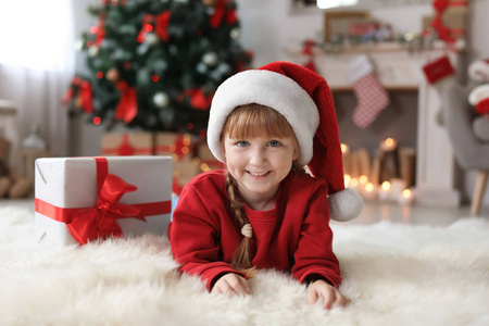 可爱的小孩在圣诞老人的帽子与圣诞礼品盒在家里
