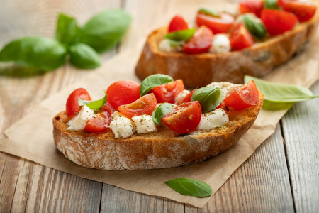 Bruschetta 有西红柿, 芝士干酪和罗勒在一个古老的乡村餐桌上。传统的意大利开胃菜或小吃, 开胃菜来