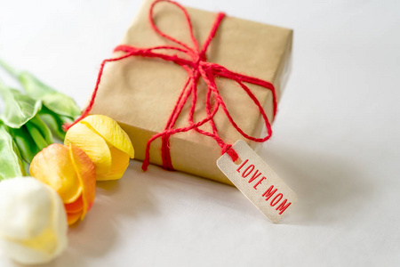 母亲节快乐的概念。礼品盒和花, 纸标签与爱妈妈文本