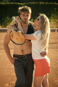 爱情序曲情侣。女朋友与网球球拍拥抱男朋友