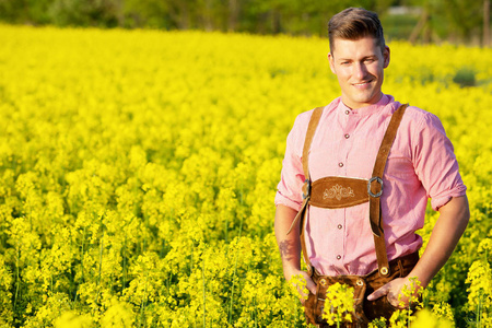金色的巴伐利亚男子站在黄色的花朵领域