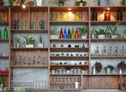 咖啡馆货架上的器皿。瓶子, 花, 玻璃, 罐子和树