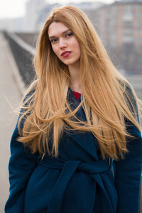 年轻美丽的金发女人穿蓝色上衣的春天 streeteet 背景上的肖像