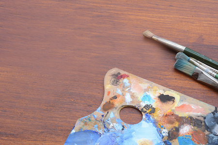 艺术家的调色板与彩色油画笔触和画笔的木质背景。艺术理念